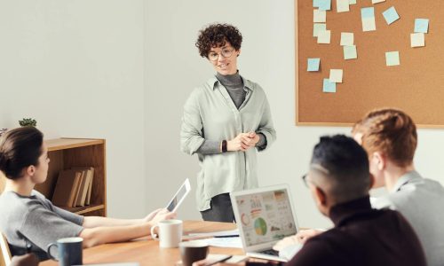 Diverse team discussing ideas during an office meeting with charts displayed on laptops.