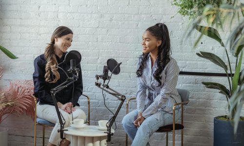 Diverse women communicating while recording voice in studio with white brick walls in daytime