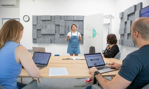 a group of people sitting around a table with laptops